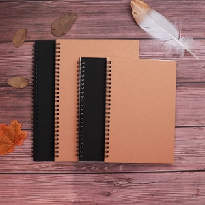 Close-up of vintage kraft paper spiral notebooks on dark wood with autumn leaves