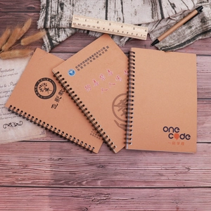 Three kraft paper spiral notebooks on wood table showing custom logo printing details