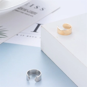 Detailed view of minimalist gold and silver C-shaped ear cuffs on a geometric background
