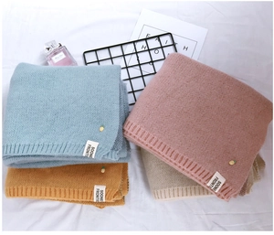 Détail d'écharpes en maille ananas colorées en bleu, rose, jaune et beige laine douce
