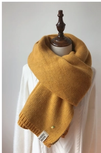Détail de l'écharpe en tricot jaune gingembre avec décor d'ananas et étiquette en tissu