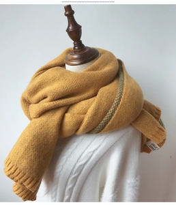 Détail d'une écharpe en grosse maille jaune gingembre avec rayures gris-vert sur mannequin