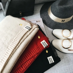 Mise à plat de bonnets tricotés en beige, rouge et noir avec broderie de petit ananas
