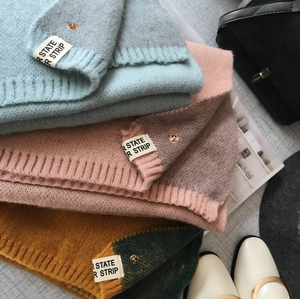 Détail d'écharpes en laine tricotée pliées en bleu clair, rose et jaune sur fond de mode