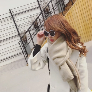 Détail d'une écharpe en maille beige doux associée à un manteau blanc classique chic