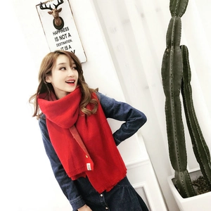Détail d'une écharpe en maille rouge avec étiquette Blooming portée par un mannequin
