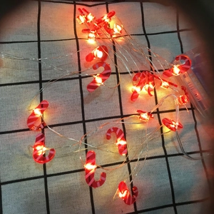 Detail of festive LED candy cane string lights with battery box on a checkered background