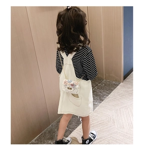 Bambina che indossa borsa a tracolla in tweed bianco con fiori di perle e catena