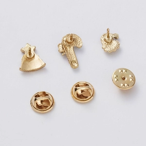 Detailed view of three gold Christmas brooches including candy cane and star motifs