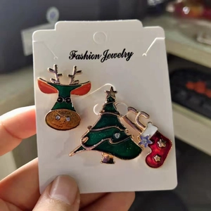 Three-piece Christmas brooch set with cartoon reindeer, tree, and sock on a display card