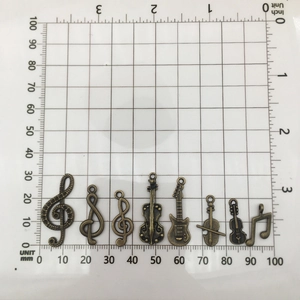 Vintage bronze musical instrument charms on measuring mat showing 15mm to 38mm dimensions
