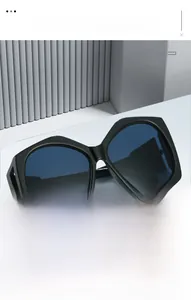 Detail view of bold black geometric sunglasses frame with blue gradient lenses on white display