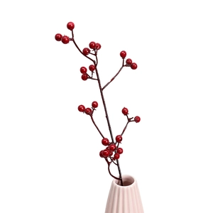 Artificial red berry branch in a pink ceramic vase for Christmas home decor