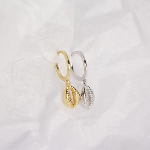 Close-up of gold and silver S925 sterling silver hoop earrings with shell pendants