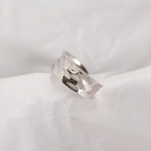 Macro shot of silver wide ring featuring a unique irregular hammered texture and metallic glow