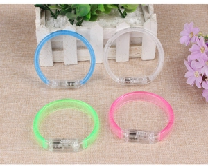 Detailed view of four colorful LED glowing bracelets on a rustic textured background