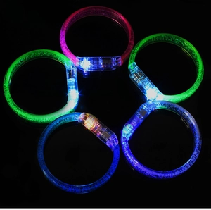 Detail of five colorful glowing LED bracelets with bubble texture on a black background