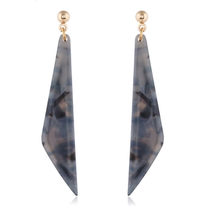 Macro detail of long geometric tortoiseshell resin earrings with gold-toned metal findings