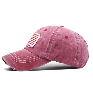 Detail of rose red washed cotton baseball cap with flag embroidery and distressed brim