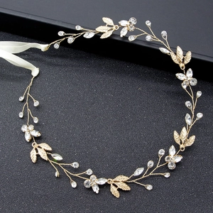 Elegant gold bridal hair band with rhinestone leaves and pearls on dark background