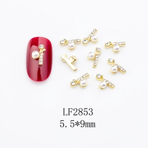 Detailed view of alloy shell nail art charms with pearls and zircons on red nails