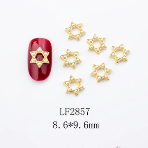 Detail of 8.6x9.6mm golden star nail charms with pearls shown on a red nail surface