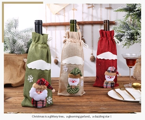 Three festive linen Christmas wine bottle covers with Santa and Snowman on a table