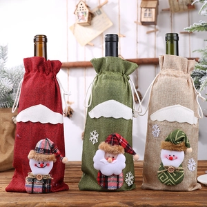 Detailed view of three festive linen wine bottle covers with Santa and Snowman designs