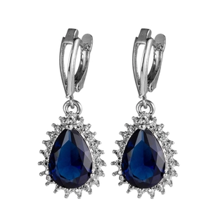 Close-up of teardrop blue sapphire earrings with silver leverback and diamond halo