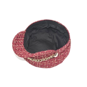 Detail of red tweed newsboy hat with gold thread weaving and decorative metal chain