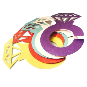 Close-up of diamond ring shaped paper napkin rings in various vibrant colors on white