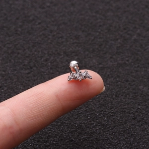 Macro shot of a silver flower tragus stud with clear zircons on a fingertip