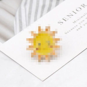 Close-up of a cute cartoon sun enamel pin with a smiling face and orange rays