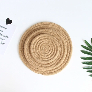 Close-up of circular woven jute placemats with a natural spiral texture on white background