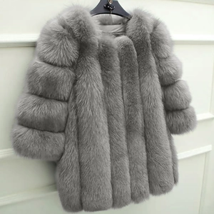 Detailed view of gray faux fur coat with long sleeves hanging against white wall