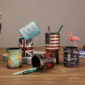 Macro view of vintage style pen holders featuring compass and map patterns on a desk