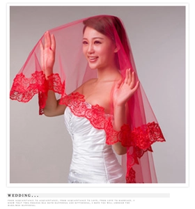 Detail of red bridal veil with delicate lace edges worn over a white wedding dress