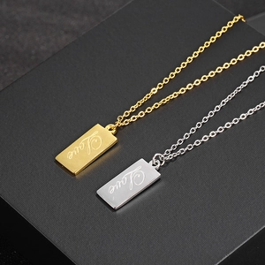 Macro view of gold and silver rectangle pendants with cursive Love engraving detail