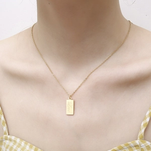 Detail view of 18K gold necklace with a rectangular pendant engraved with Love script