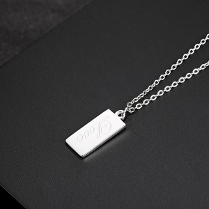 Macro detail of silver square pendant engraved with Love script on textured background