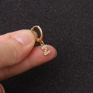 Détail macro boucle d'oreille lettre Z dorée avec zircone tenue dans la main