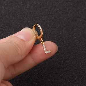 Gros plan d'une boucle d'oreille anneau dorée avec pendentif lettre L en zircon