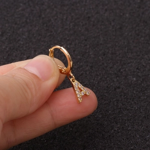Détail d'un pendentif boucle d'oreille lettre A dorée avec zircons tenu par les doigts