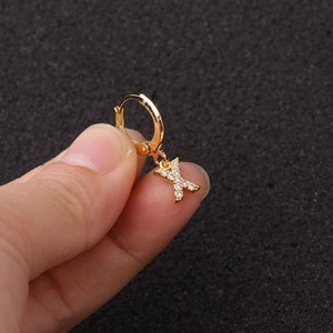 Gros plan d'un ear cuff doré avec pendentif lettre 'X' serti de zircons brillants