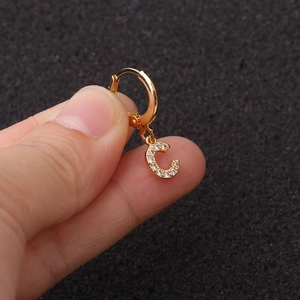 Détail d'une créole lettre C dorée ornée de pierres de zircone cubique transparentes