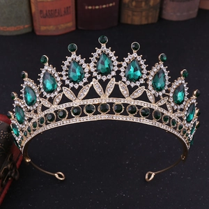Detailed macro view of vintage gold crown with green teardrop gems and white rhinestones