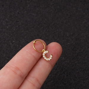Gros plan d'une boucle d'oreille lettre C avec zircon brillant sur anneau perlé doré