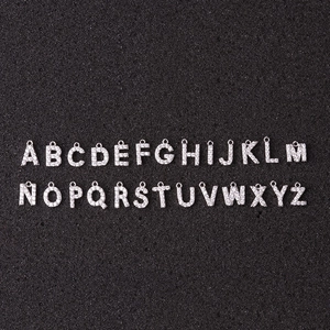 Collier créatif avec 26 pendentifs de lettres en zircone sur un fond sombre texturé