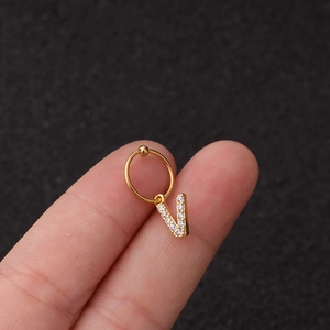 Gros plan d'une boucle d'oreille dorée en forme de V sertie de zircons brillants