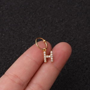Gros plan du pendentif lettre H doré avec zircons blancs sur un anneau en acier